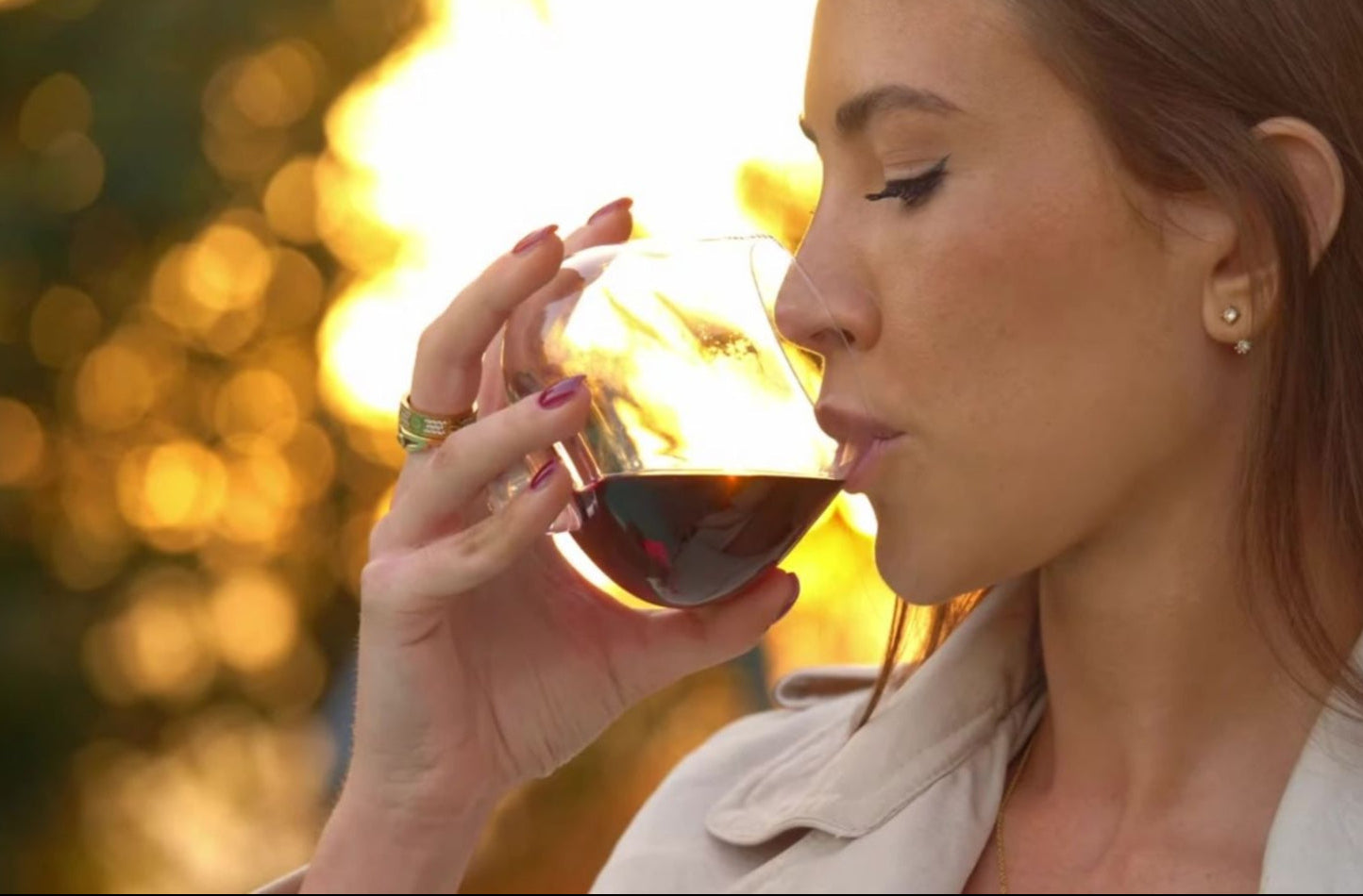 Woman holding an EQUILO glass at golden hour, just about to take a sip — warm sunlight and soft focus capture the elegance and emotion of the moment.