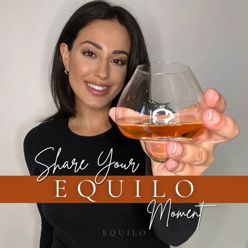 Woman holding EQUILO No.1 glass with “Share your EQUILO moment” competition banner